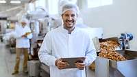 Mann im weißen Kittel mit Haarnetz in einer Fabrik. Pommes Frites Herstellung.