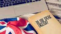 UK-Flagge und Buch liegen vor einem Laptop